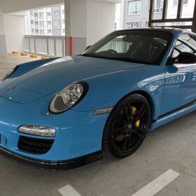 Blue Porsche 911 coupe in a front three-quarter view in a parking garage
